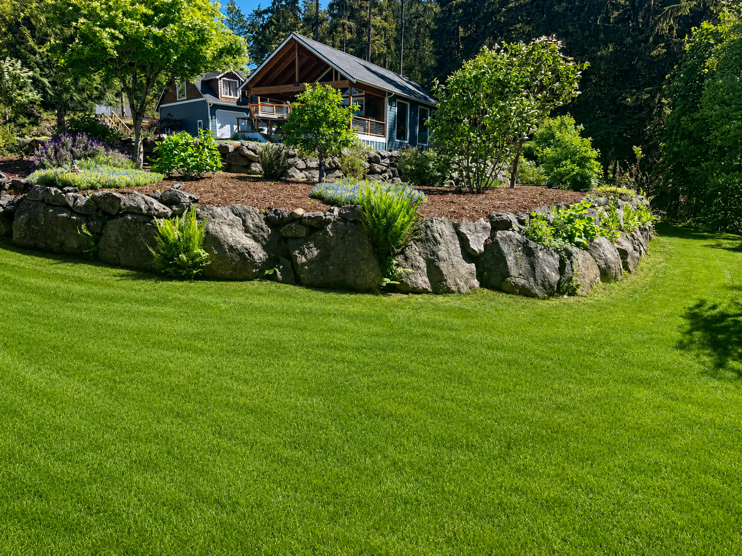 Finished natural boulder retaining wall surrounding a lawn